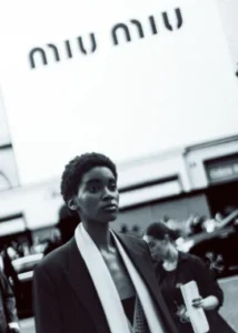 Modelo em ambiente urbano com referência à Miu Miu, marca de roupas ligada à moda jovem e ousada.