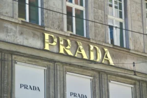 Fachada da loja Prada com logotipo dourado, referência em moda sofisticada e design contemporâneo.