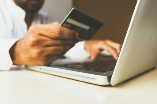 Homem usando cartão de crédito no notebook para compra online, ilustrando risco de chargeback e fraudes digitais.