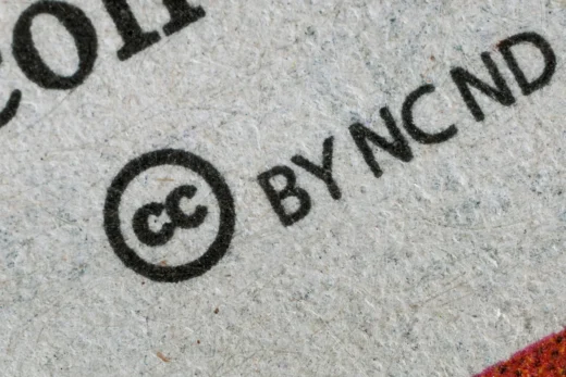 Símbolo Creative Commons impresso em papel texturizado, representando licenças abertas de uso e compartilhamento de conteúdo.